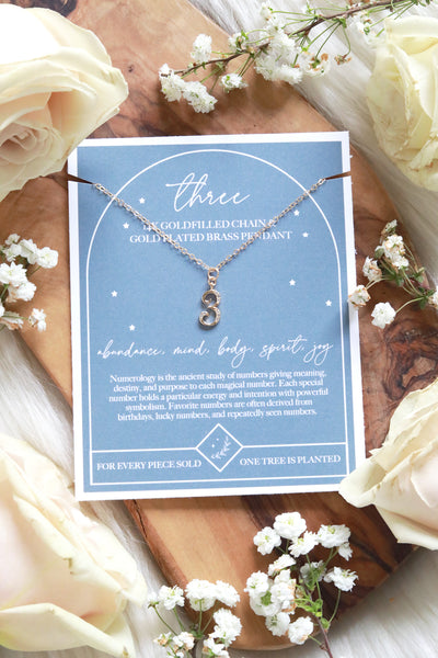 A SET OF THREE : A GOLD PLATED CURIOSITÉ NECKLACE , A GOLD PLATED